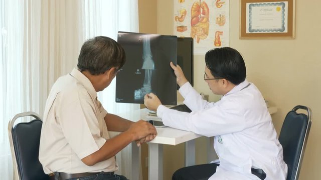 Doctor is showing x-ray film and explaining to patient