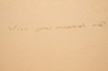 Fototapeta na wymiar Handwritten Will you married me in the sand on the beach
