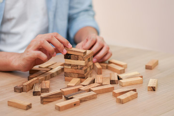 close up businessman hand holding wooden block for playing created tower , business vision concept