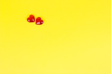 Two yellow hearts on a yellow cardboard background.