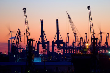 Silhouette of container gantry cranes in the harbour of Hamburg, Germany at sunset. 