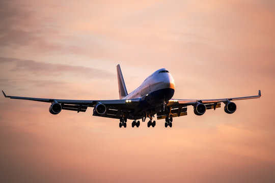 Large passenger airplane landing at international airport at sunset.