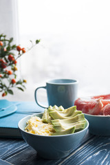Healthy breakfast: eggs and avocados, grapefruit and a cup of coffee. The food is on a wooden tray.