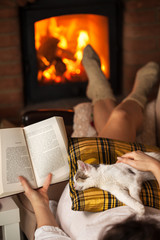 Woman reading by the fire - relaxing with her cat
