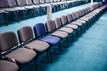 Many comfortable chairs in empty conference hall. Selective focus. Different from others.