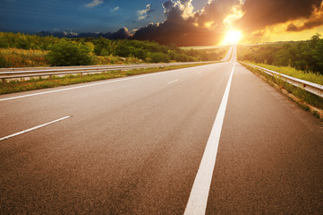 An empty countryside road against a night sky with sunset