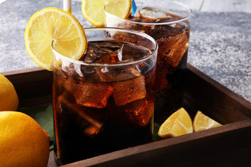 Softdrink with ice cubes, lemon and straw in glass