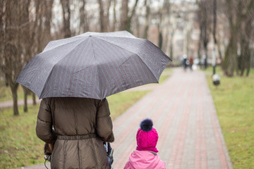 Mom and daughter   walking together with stroller