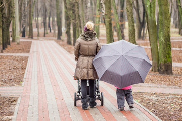 Mom and daughter   walking together with stroller