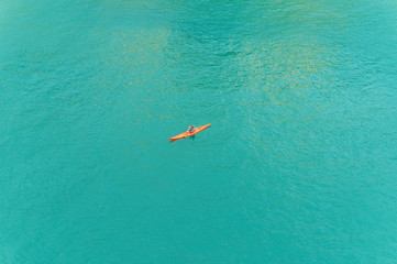 Obraz premium human in red kayak in the middle of the blue sea top view
