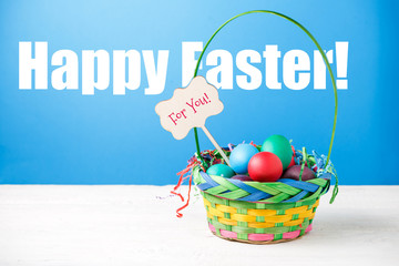 Photo of basket with colorful eggs with wish for happy Easter
