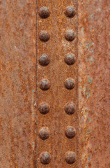 Industrial abstract textured vertical pattern. Vertical row of rusted rivets selective focus