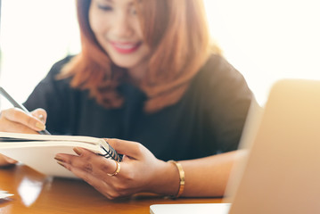 Asian stylish glasses woman designer wear black dress and red lips happiness writing a notebook in selective focus..