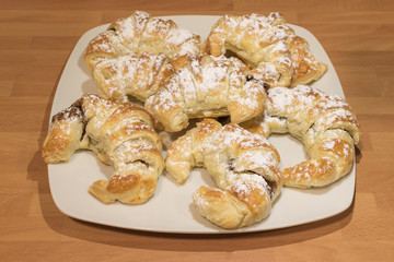 Some croissant filled on chocolate with sugar glass on top on a ceramic plate
