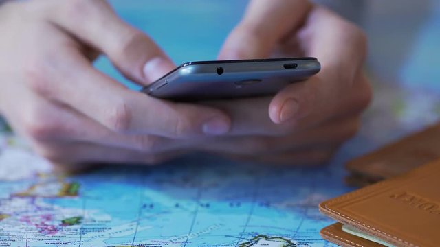 Closeup male hands holding smartphone, booking tickets and hotel in tourists app