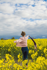 Happy, independent,  girl runs in the field with rapeseed in windy weather waving  waving scarf