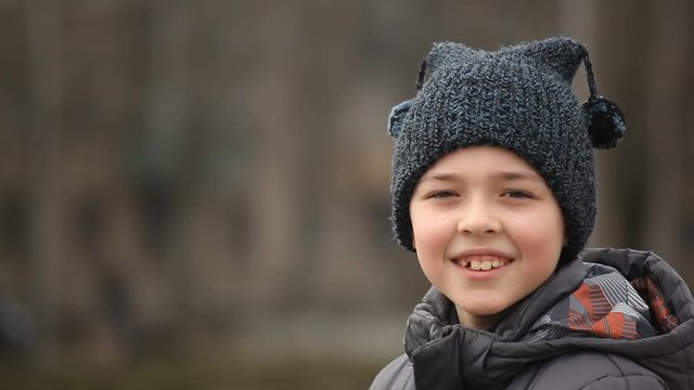 An original view of a nine-year-old boy who stands outdoors in a woollen hat with two waving balls. He thinks about his Christmas holidays