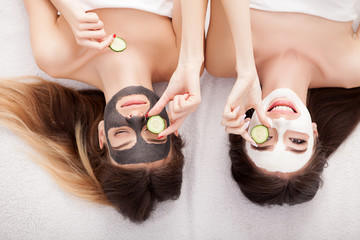 A picture of two girls friends relaxing with facial masks on over white background