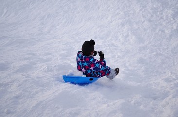 Fototapeta na wymiar スキー場でそり遊びをする子供