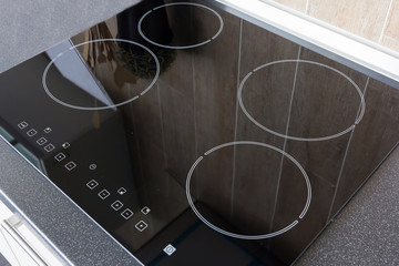 Close up view of an electrical kitchen induction ceramic hob with kitchen furniture