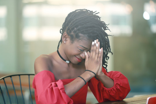 Smiling African girl touching forehead during prayer
