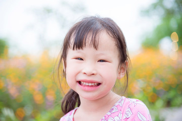 Closeup of little asian girl smiling at camera in flower garden