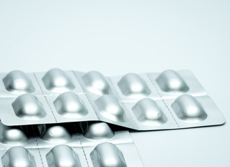 Tablet pills in silver aluminium blister pack packaging on blurred background of pack of pills with...