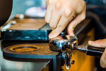Barista using tamper to tamp coffee grounds in the portafilter