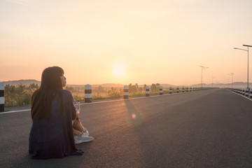 Young asian woman sitting on the road at sunrise