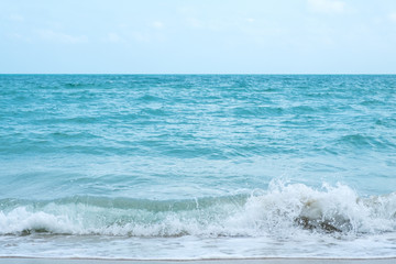 Waves on tropical white beach with blue sky background