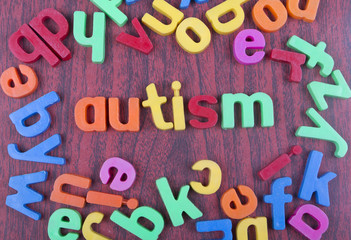 Autism text with scattered alphabets on woden table.