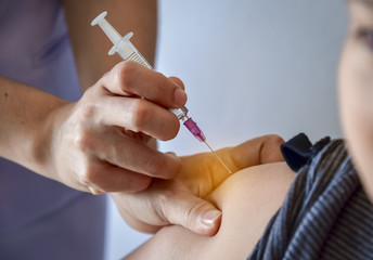 Nurse injucting syringe of vaccine to patient in hospital