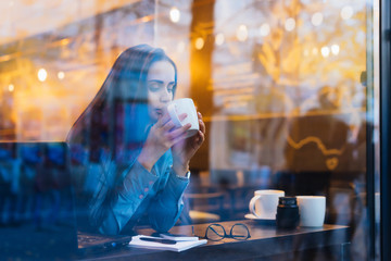 outside the window a woman is sitting and drinking tea