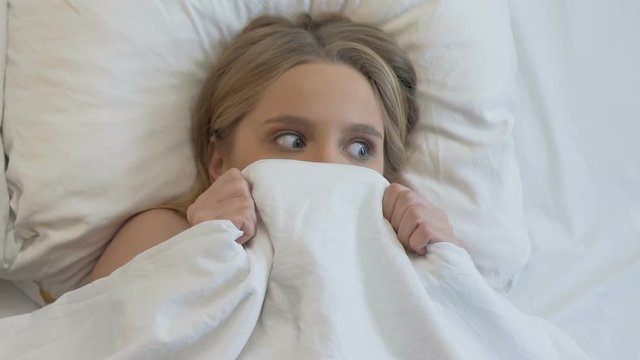 Pretty young woman is caught in bed with boyfriend, feeling shocked, surprise