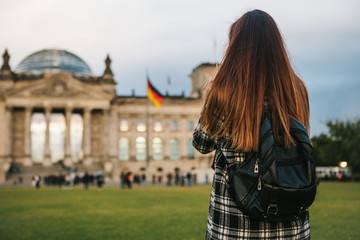 A tourist girl with a backpack next to the building called the Reichstag in Berlin in Germany takes...