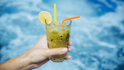 Cocktail in woman's hand near swimming pool close up
