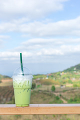 Iced Green tea matcha latte on wooden table in coffee shop.  Matcha is finely ground powder of specially grown and processed green tea leaves