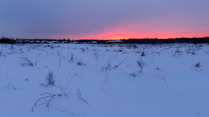 Panorama winter of red sunset over the snow-covered village.