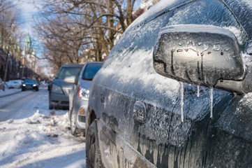 Thick layer of ice on car after freezing rain in Montreal, Canada - Close up of outside mirror covered with ice