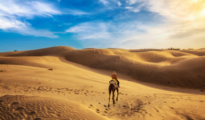 Tourist enjoy camel ride at the Thar desert Jaisalmer, Rajasthan, India at sunset.	