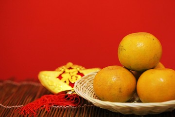 Chinese New year orange in basket with ingot of Chinese language meaning of Happiness and Wealthy and orange on red background