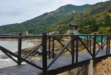 Obraz premium Wooden suspension bridge between mountains and sea in China