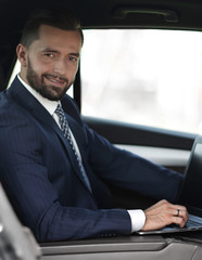 Close-up of a businessman with a laptop sitting in the car