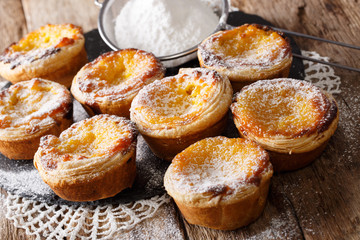 Crispy Portuguese dessert Pastel de nata with custard and powdered sugar close-up on the table. horizontal