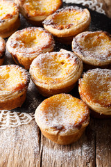 Portuguese cuisine: pastel de nata dessert with a cream and powdered sugar close-up on the table. vertical