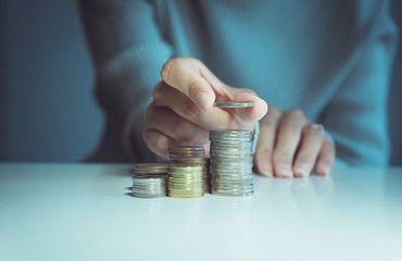 Close up of hand putting coins stacks on a table,Saving money concept