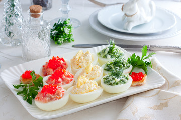 Festive serving of stuffed eggs with filling options - red, yellow, green. Selective focus, horizontal