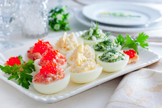 Festive serving of stuffed eggs with filling options - red, yellow, green. Selective focus, horizontal