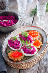 Snack of stuffed eggs with beets and fish filling on a wooden table, rustic style, selective focus