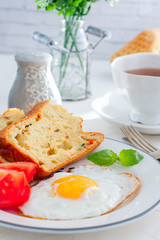 Fresh breakfast with scrambled eggs, fresh tomatoes and sliced pieces of muffins with mozzarella and sun-dried tomatoes, selective focus